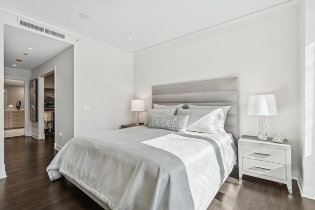 bedroom with baseboards, visible vents, a walk in closet, and wood finished floors