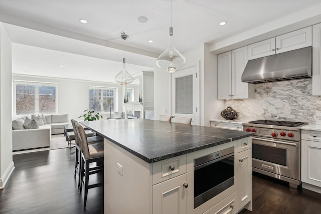 kitchen featuring dark wood-style floors, open floor plan, stainless steel appliances, under cabinet range hood, and backsplash