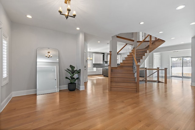 entrance foyer with recessed lighting, a notable chandelier, baseboards, light wood-style floors, and stairway