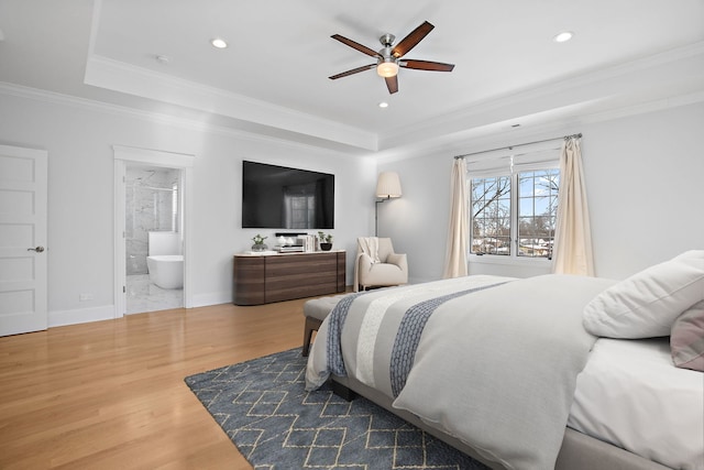 bedroom with recessed lighting, wood finished floors, baseboards, a tray ceiling, and crown molding