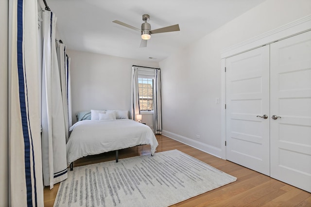 bedroom featuring a closet, ceiling fan, baseboards, and wood finished floors