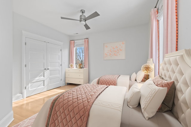 bedroom with light wood-style flooring, ceiling fan, and a closet