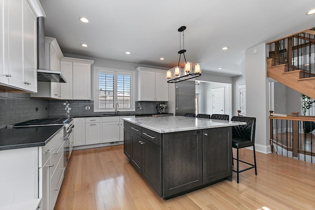 kitchen with white cabinets, a kitchen island, decorative light fixtures, and a sink