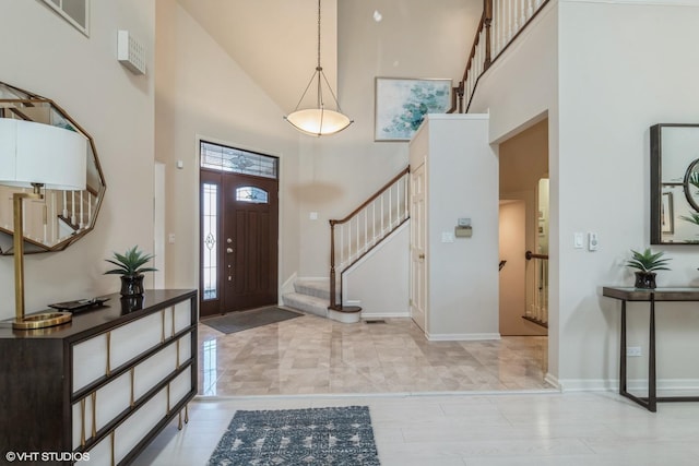 foyer with stairway, visible vents, baseboards, and a towering ceiling