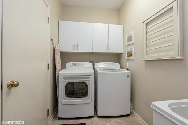 laundry room with separate washer and dryer, cabinet space, and baseboards