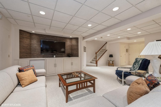 carpeted living area with stairway, recessed lighting, and a paneled ceiling