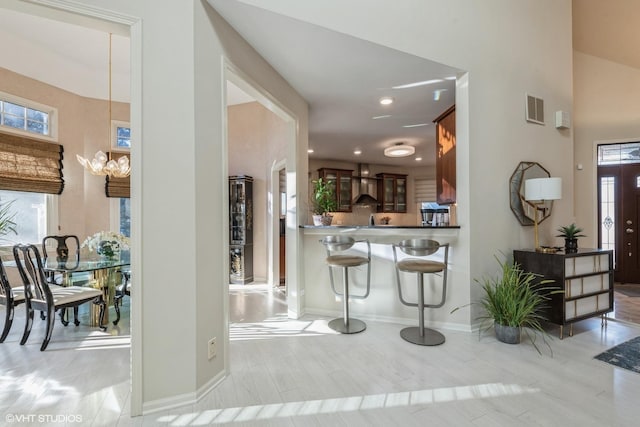 foyer entrance featuring visible vents, a notable chandelier, a healthy amount of sunlight, and wood finished floors