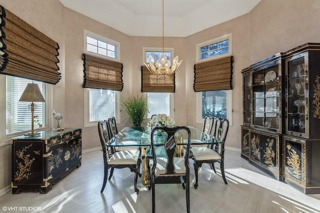 dining area featuring a notable chandelier, wood finished floors, plenty of natural light, and baseboards