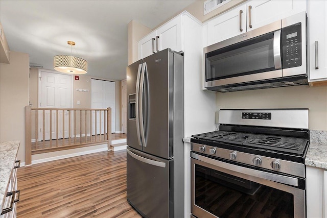 kitchen with hanging light fixtures, stainless steel appliances, light stone counters, light hardwood / wood-style floors, and white cabinetry