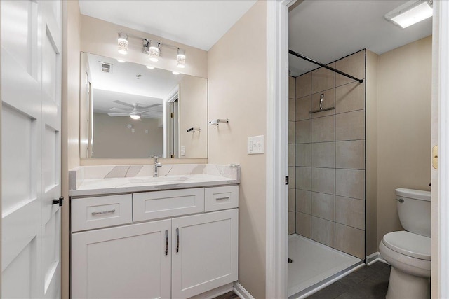 bathroom featuring ceiling fan, a tile shower, vanity, and toilet