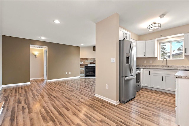 kitchen with sink, stainless steel appliances, white cabinets, and light hardwood / wood-style floors