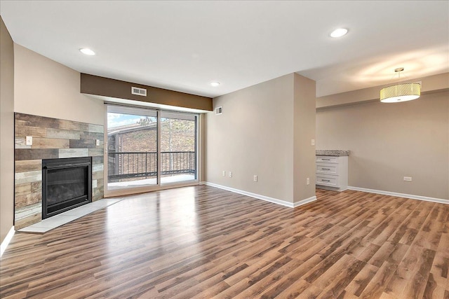 unfurnished living room with a tile fireplace and hardwood / wood-style floors