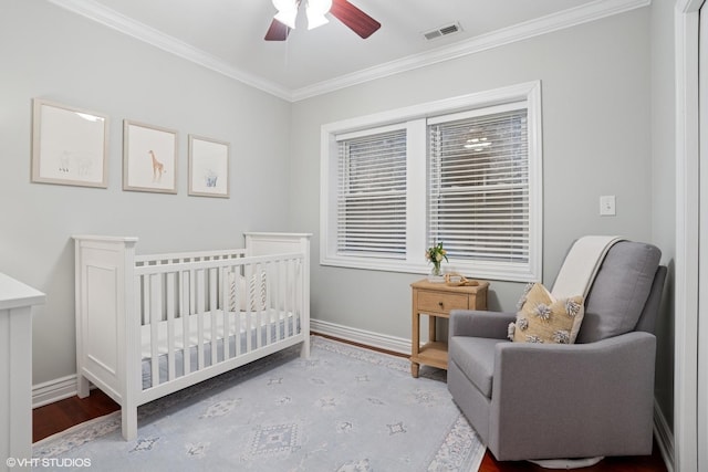 bedroom with a nursery area, crown molding, visible vents, and baseboards