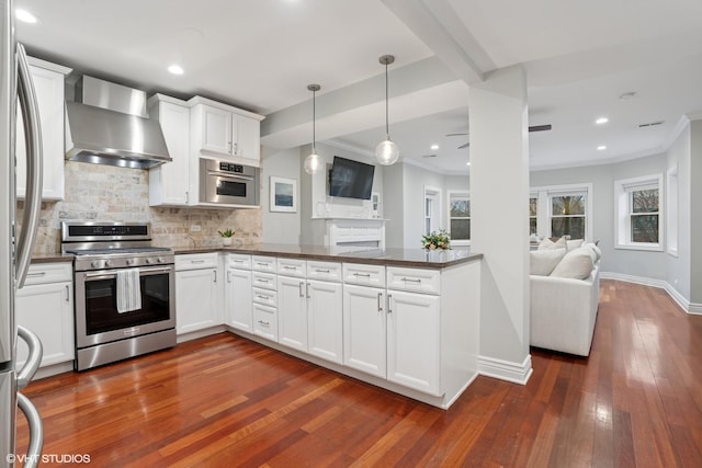 kitchen featuring stainless steel appliances, dark countertops, open floor plan, and wall chimney range hood