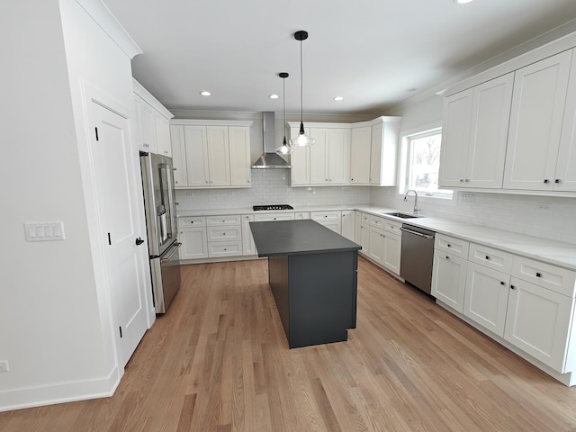 kitchen featuring wall chimney exhaust hood, appliances with stainless steel finishes, a kitchen island, pendant lighting, and white cabinets