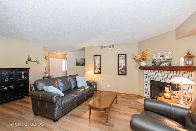 living room with a textured ceiling, a fireplace, wood finished floors, and visible vents