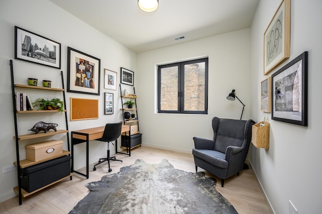 office area with light wood-type flooring, visible vents, and baseboards