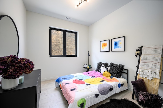 bedroom with light wood finished floors, visible vents, and baseboards