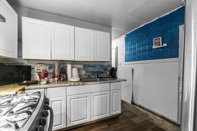 kitchen featuring gas range, dark hardwood / wood-style floors, sink, and white cabinets