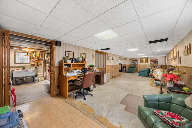 office area featuring wood walls, a drop ceiling, and a wainscoted wall