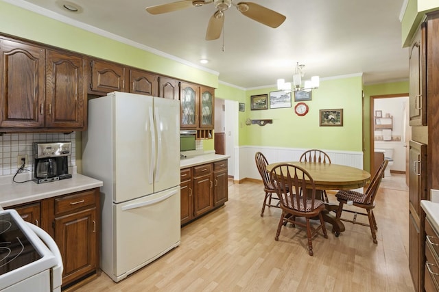 kitchen with white appliances, light hardwood / wood-style floors, pendant lighting, and ornamental molding