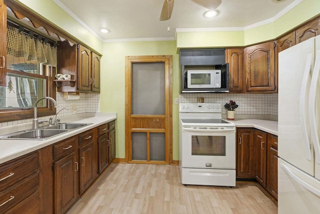 kitchen with white appliances, light wood-type flooring, decorative backsplash, crown molding, and sink