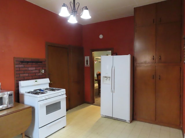 kitchen featuring white appliances, pendant lighting, and an inviting chandelier