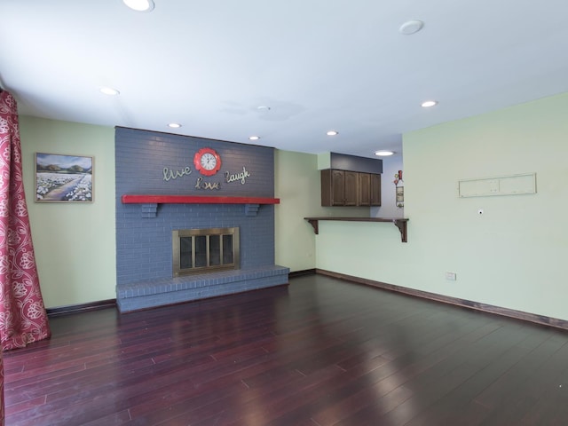 unfurnished living room with a brick fireplace and dark hardwood / wood-style floors