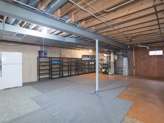 basement featuring gas water heater, heating unit, and white refrigerator