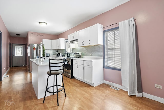 kitchen with a kitchen island, a breakfast bar area, white cabinets, decorative backsplash, and stainless steel appliances