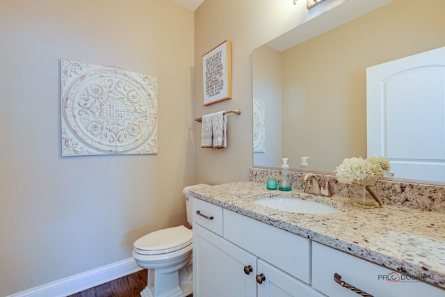 half bath featuring baseboards, vanity, toilet, and wood finished floors