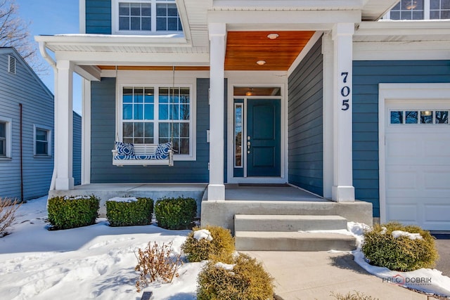 snow covered property entrance with a garage