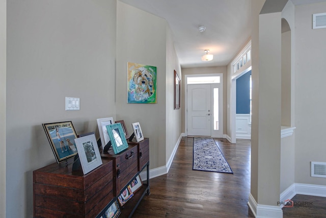 foyer entrance with dark wood finished floors, visible vents, and baseboards