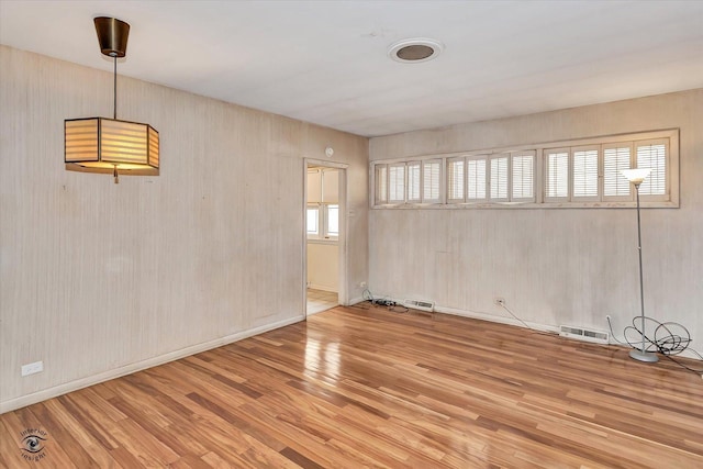 unfurnished room featuring wood finished floors, visible vents, and baseboards