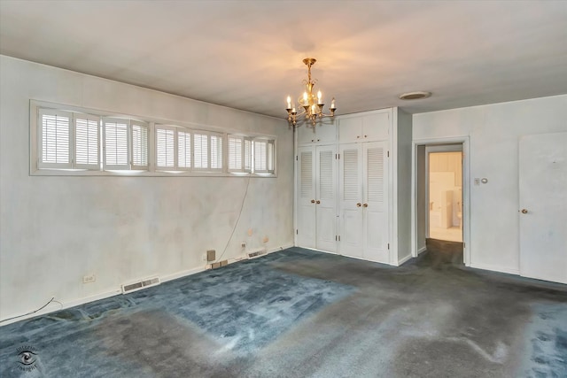 unfurnished room featuring dark carpet, plenty of natural light, visible vents, and a notable chandelier