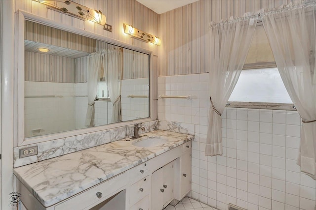 bathroom featuring wallpapered walls, tile walls, and vanity