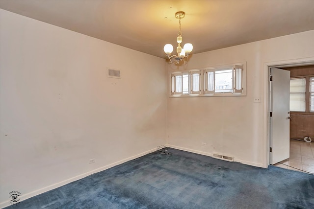 spare room featuring dark colored carpet, visible vents, a notable chandelier, and baseboards