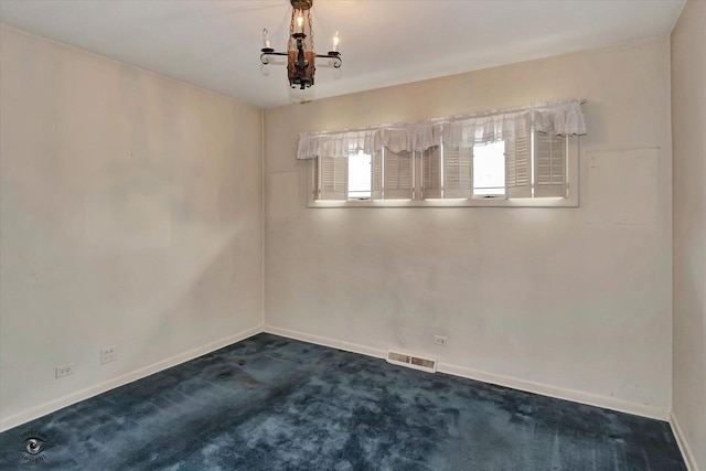 spare room featuring a notable chandelier, dark carpet, visible vents, and baseboards