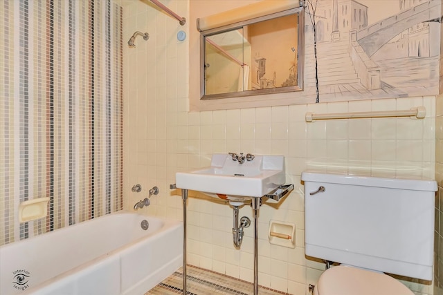 bathroom with toilet, a sink, bathtub / shower combination, and tile walls