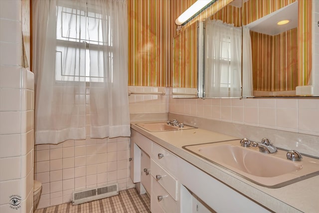 full bathroom featuring visible vents, a sink, tile walls, and wallpapered walls