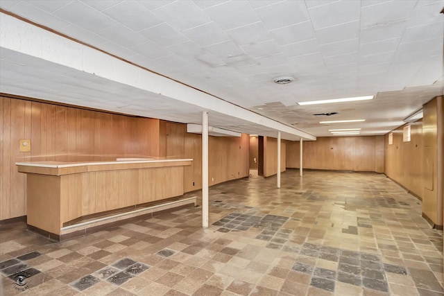 finished basement featuring a bar and wood walls