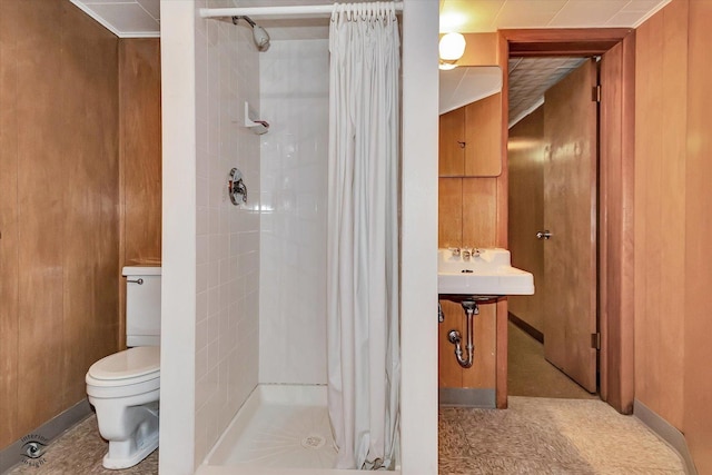 full bath with toilet, wood walls, a shower stall, and a sink