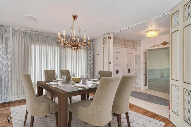 dining space with wallpapered walls, light wood finished floors, and an inviting chandelier