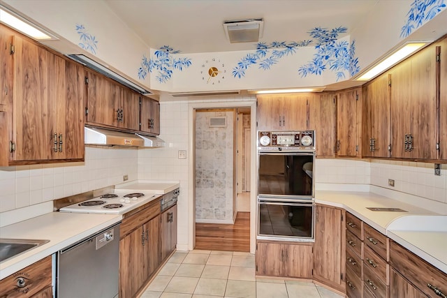 kitchen with dobule oven black, dishwasher, white electric cooktop, brown cabinets, and under cabinet range hood