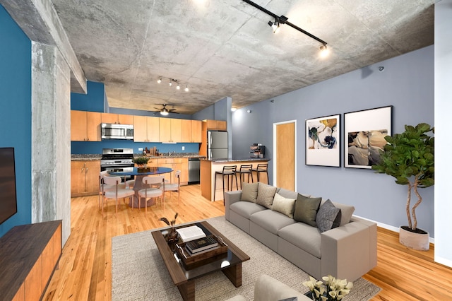 living room with light wood finished floors, ceiling fan, and baseboards