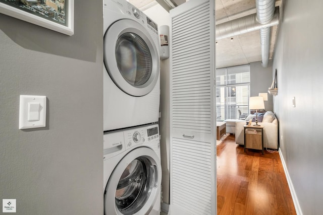 laundry area with hardwood / wood-style floors and stacked washer / dryer