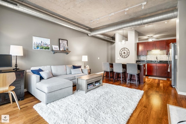 living room featuring baseboards, visible vents, track lighting, and wood finished floors