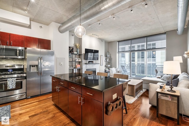 kitchen featuring appliances with stainless steel finishes, track lighting, a center island, and hardwood / wood-style flooring