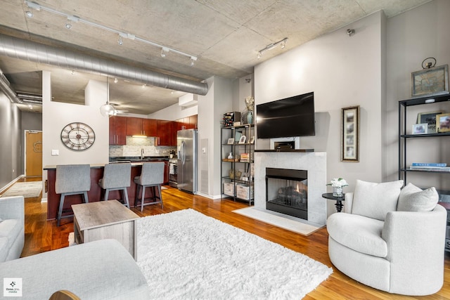 living room with hardwood / wood-style flooring, a tile fireplace, ceiling fan, and track lighting