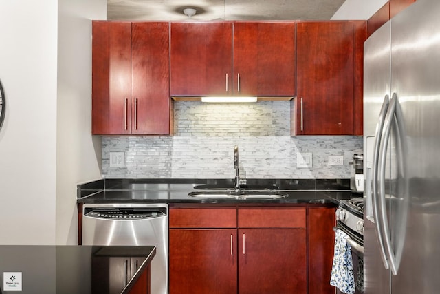 kitchen featuring appliances with stainless steel finishes, sink, tasteful backsplash, and dark stone counters